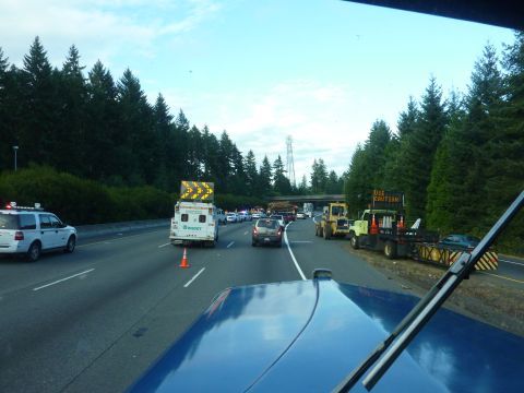 1981 Kenworth W900A - A traffic incident has caused a significant backup on the highway, with emergency and construction vehicles present.
