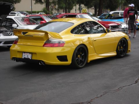 1998 Ford Crown Victoria - A yellow Porsche 911 is parked among other vehicles at an outdoor gathering.