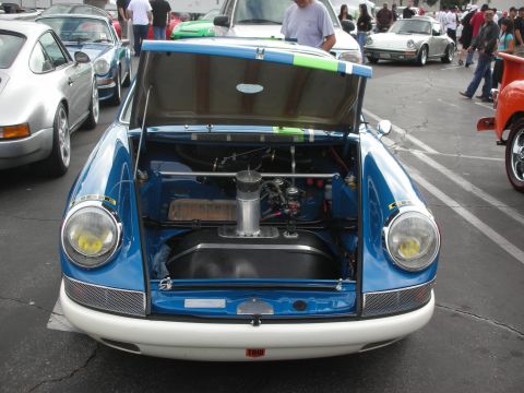 1998 Ford Crown Victoria - A blue and white vintage sports car is parked with its hood open, displaying its engine and fuel tank at a car meet.