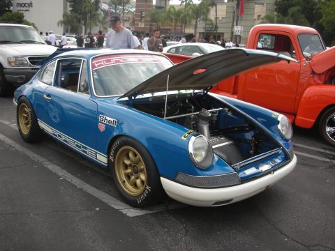 1998 Ford Crown Victoria - A blue Porsche 911 with its hood open is parked next to an orange pickup truck.
