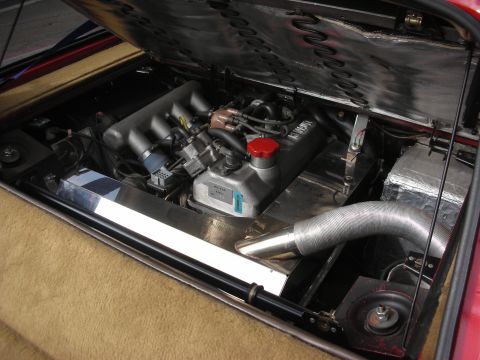 1998 Ford Crown Victoria - The engine bay of a vehicle, a V8 engine with a red cap and silver intake piping.