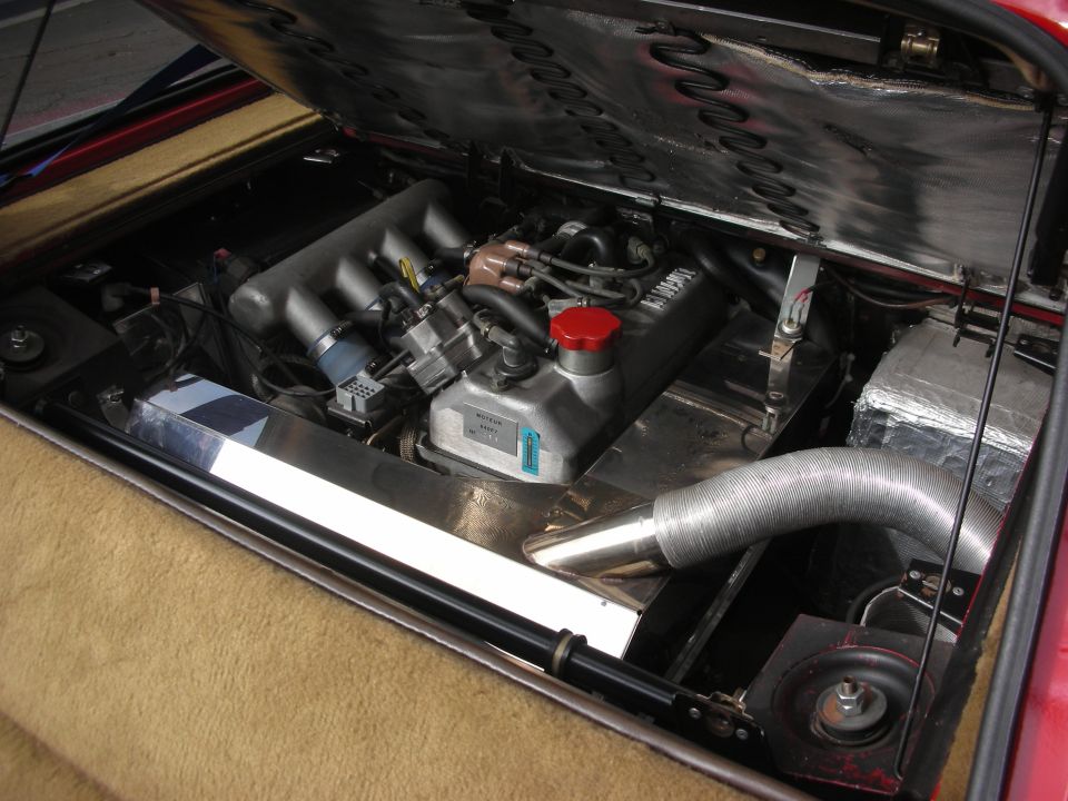 Engine bay with V8 engine, red cap, and silver intake tube
