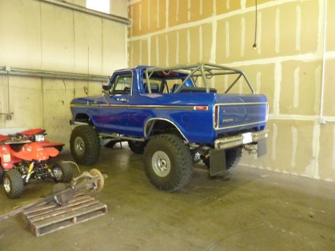 1981 Kenworth W900A - Modified blue Ford Bronco with a roll cage and off-road tires, parked next to an ATV.