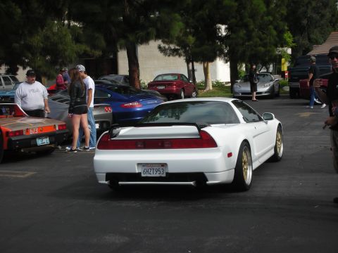 1998 Ford Crown Victoria - A white sports car is parked among other vehicles at an outdoor gathering.