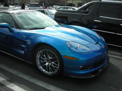 1998 Ford Crown Victoria - A bright blue Chevrolet Corvette Z06 is parked in a lot, with a black SUV behind it.