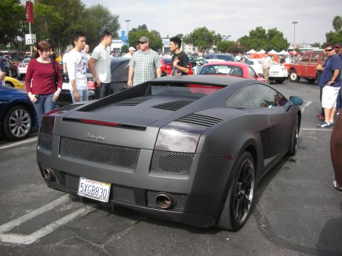 1998 Ford Crown Victoria - A group of people stand around a matte gray Lamborghini Gallardo at a car show.