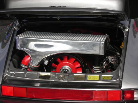 1998 Ford Crown Victoria - The rear engine compartment of a Porsche features a polished intercooler and a bright red cooling fan.
