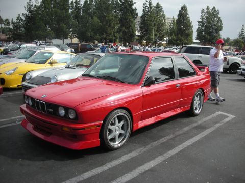 1998 Ford Crown Victoria - Red BMW E30 coupe with aftermarket wheels and body kit at a car meet.
