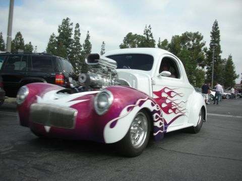 1998 Ford Crown Victoria - A custom hot rod with a prominent supercharger and flame graphics is parked at an outdoor event.