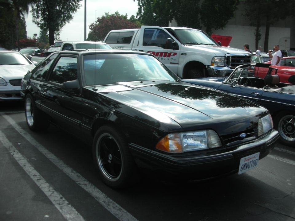 Black 1987 Ford Mustang hatchback parked in a lot with other cars