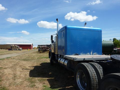 1981 Kenworth W900A - A blue semi-truck cab and chassis is parked outdoors on a sunny day with a few clouds in the sky.