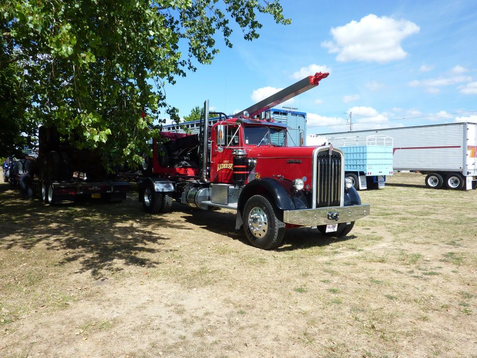 Red tow truck with a crane, chrome bumper, and black fenders. It is parked on a grassy field