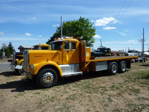 1981 Kenworth W900A - A yellow flatbed truck is parked outdoors with another truck visible behind it.