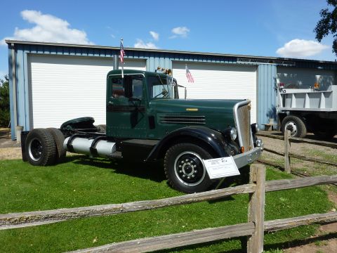 1981 Kenworth W900A - A vintage green truck tractor is displayed on a sunny day, with another truck visible in the background.