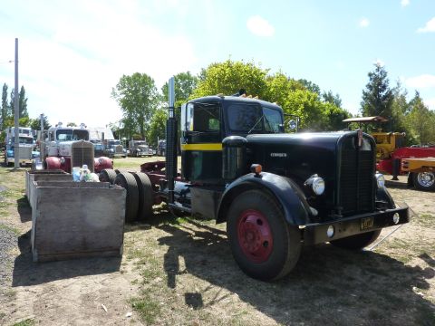 1981 Kenworth W900A - A black Kenworth semi-truck is parked in a lot with other trucks visible in the background.