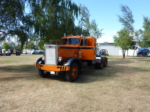 1981 Kenworth W900A - An orange semi-truck with a distinctive grille and black trim sits parked outdoors.