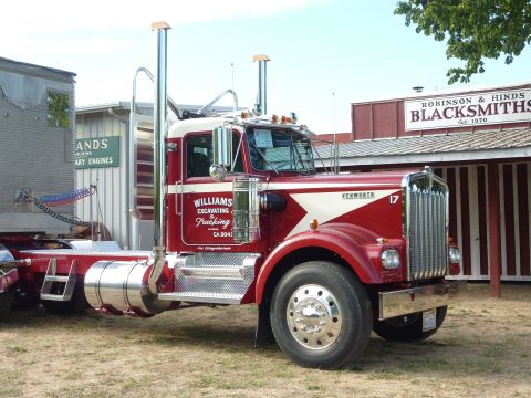 1981 Kenworth W900A - A red and white Kenworth truck is parked in front of a building with 'Robinson & Hinds Blacksmiths' signage.
