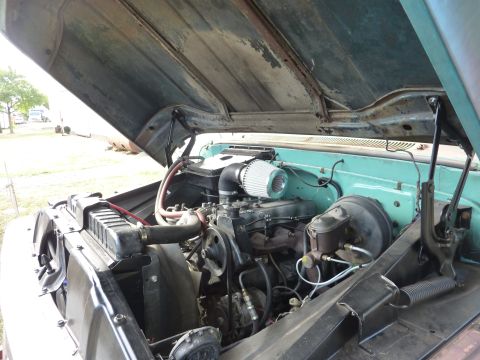 1981 Kenworth W900A - The engine bay of a truck, an aftermarket air intake and a turquoise firewall, with the hood open.