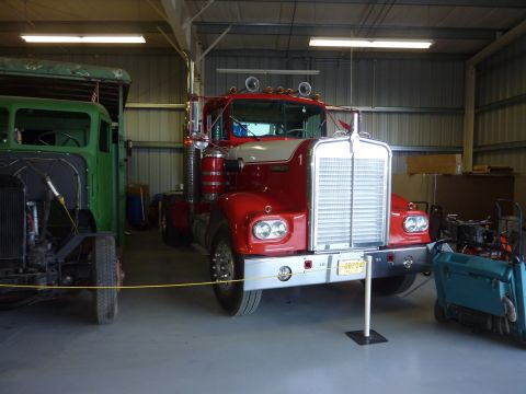 1981 Kenworth W900A - A red and white Kenworth W900A truck is parked next to a green truck in a garage.