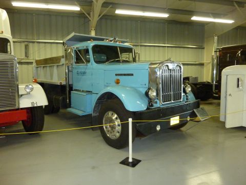 1981 Kenworth W900A - A light blue dump truck is parked inside a building with other trucks.