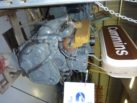 1981 Kenworth W900A - A gray Cummins engine is displayed with a prominent Cummins sign. The engine appears to be a standalone exhibit.
