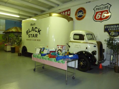 1981 Kenworth W900A - A vintage Black Star beer truck is displayed indoors with a table of items in front of it.