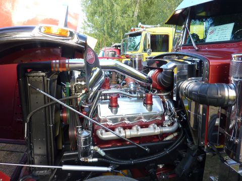 1981 Kenworth W900A - The detailed engine compartment of a large truck is shown, with other trucks parked nearby.