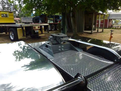 1981 Kenworth W900A - Close-up of a fifth wheel hitch on a trailer, with other vehicles visible in the background.