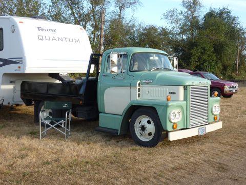 1981 Kenworth W900A - A vintage green and white flatbed truck is parked on a grassy field next to a large trailer.
