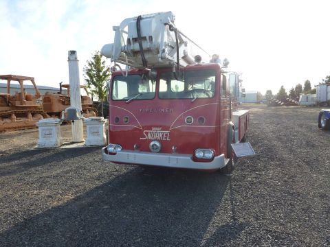 1981 Kenworth W900A - A red fire truck with a snorkel apparatus is parked outdoors, with other vehicles and structures in the background.