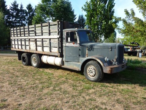 1981 Kenworth W900A - A vintage flatbed truck with a weathered appearance sits outdoors on a sunny day.