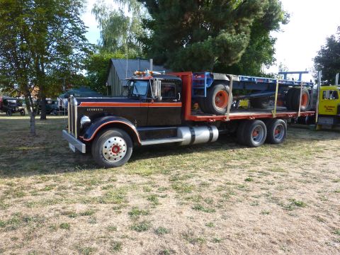 1981 Kenworth W900A - A 1981 Kenworth W900A flatbed truck is seen with a trailer loaded on its bed.