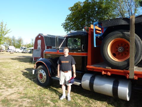 1981 Kenworth W900A - A man poses in front of a classic black and orange semi-truck, likely a 1981 Kenworth W900A, on a sunny day.