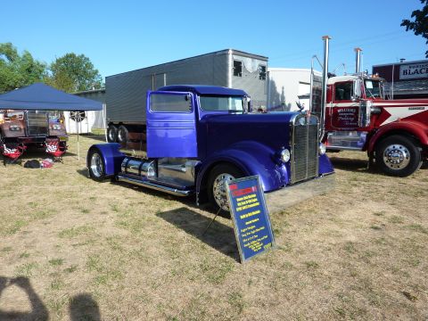 1981 Kenworth W900A - A customized 1981 Kenworth W900A semi-truck cab is displayed at an outdoor event with other vehicles.