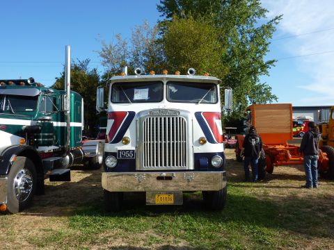 1981 Kenworth W900A - A classic truck with a prominent grille and a 1955 badge is parked outdoors next to another large vehicle.