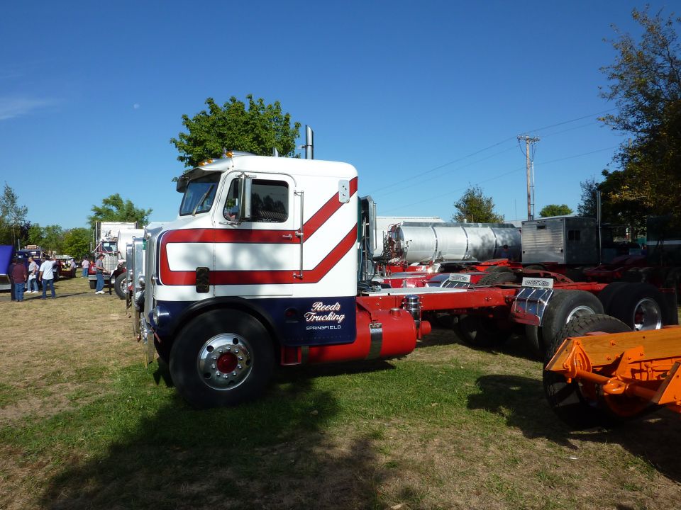 White and red Reed's Trucking cabover semi tractor on grass at a truck show