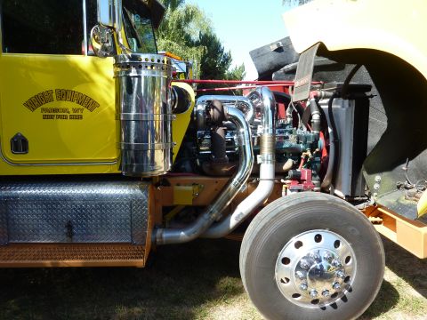 1981 Kenworth W900A - Close-up view of a yellow truck's engine compartment and side, chrome exhaust and a prominent tire.
