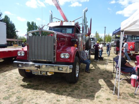 1981 Kenworth W900A - A red 1981 Kenworth W900A semi-truck is parked at an outdoor event with other vehicles and attendees.