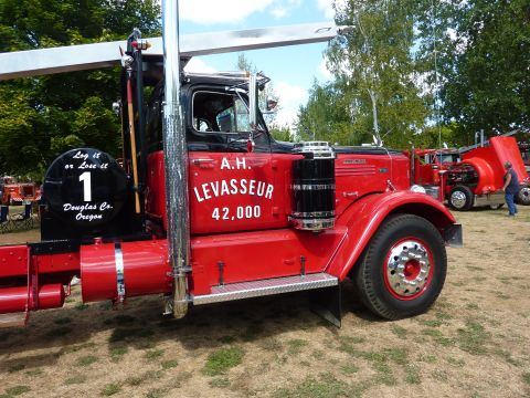 1981 Kenworth W900A - A red truck with a crane and the name A.H. LEVASSEUR and the number 42,000 painted on its side is seen at an outdoor event.