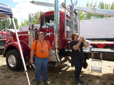 1981 Kenworth W900A - Two men stand near a large red semi-truck at an outdoor event.