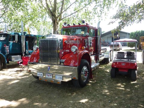 1981 Kenworth W900A - A classic red semi-truck is parked outdoors, with other vehicles and a building in the background.