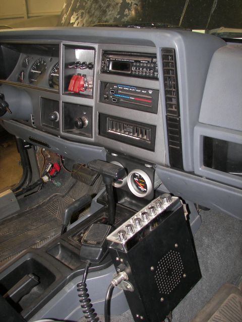 1988 Ford Bronco - The interior of a Jeep Cherokee shows the dashboard, center console, and a CB radio mounted below the dash.