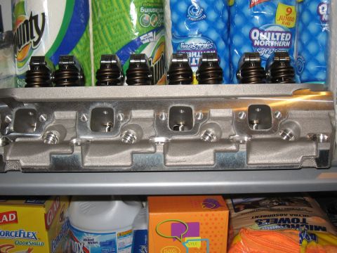 1994 Ford Bronco - A close-up view of an engine cylinder head, with automotive parts and household items in the background.