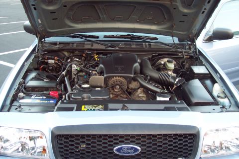 2001 Ford Crown Victoria - The engine bay of a light blue 2001 Ford Crown Victoria is visible with the hood raised.