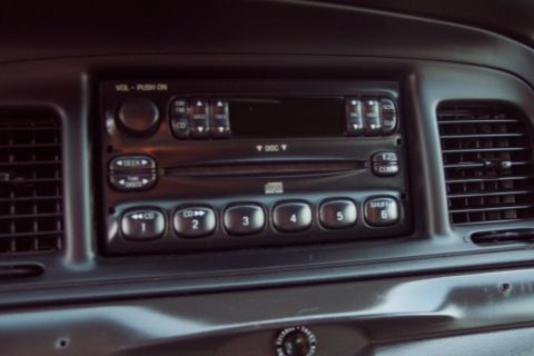 2001 Ford Crown Victoria - Close-up of a car's dashboard, focusing on the radio unit and adjacent air conditioning vents.