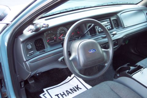 2001 Ford Crown Victoria - The interior of a car, showing the dashboard, steering wheel, and a thank you sign on the floor mat.