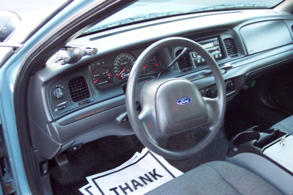 Ford steering wheel and dashboard from the driver's seat. There's a 'THANK YOU' sign on the floor
