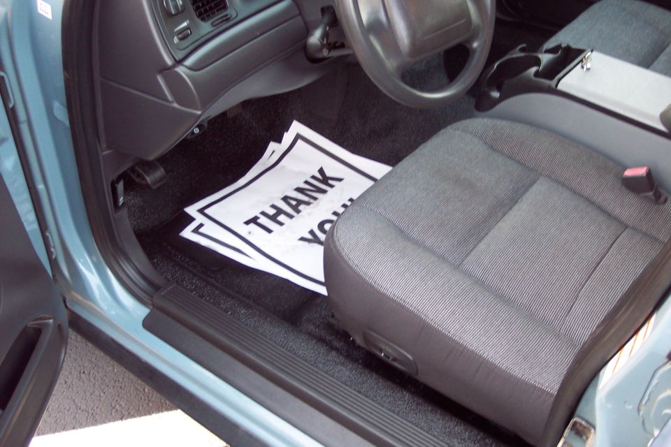 Interior of a blue 2001 Ford Crown Victoria showing the driver's seat, dashboard, and floor mats with "THANK YOU" text