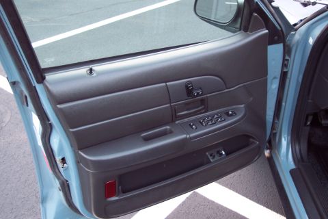 2001 Ford Crown Victoria - The interior door panel of a vehicle is shown, power window controls and a door handle.