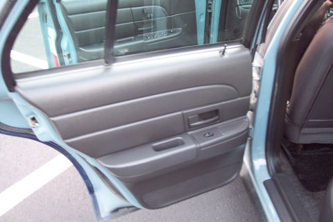 2001 Ford Crown Victoria - The interior of a car shows the rear door panel and a portion of the back seat.